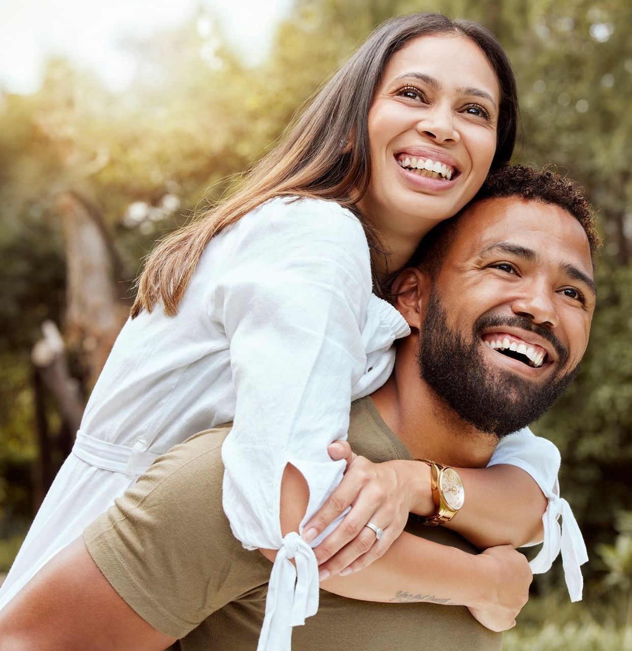 A man is carrying a woman on his back and they are smiling.