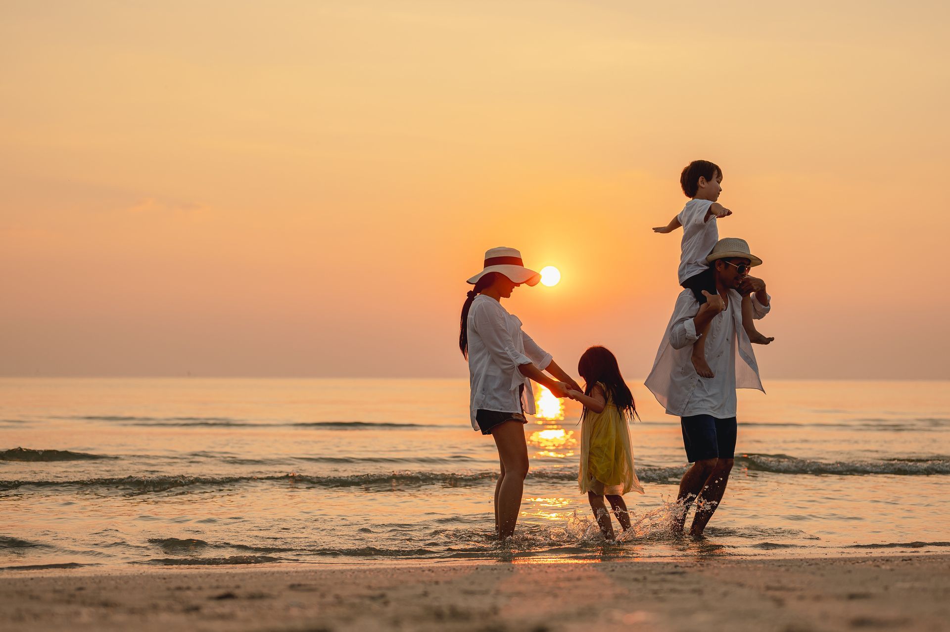 A family is walking on the beach at sunset.