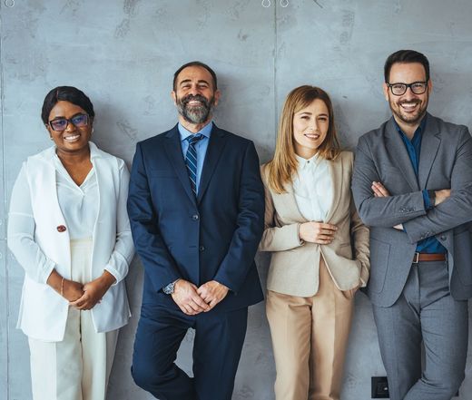 A group of business people standing next to each other in front of a wall.