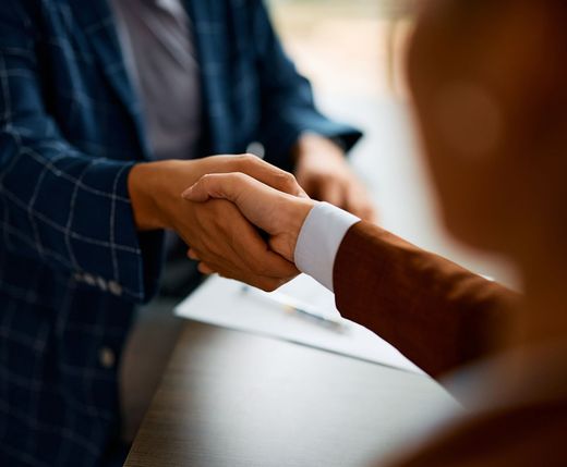 A man and a woman are shaking hands over a table.