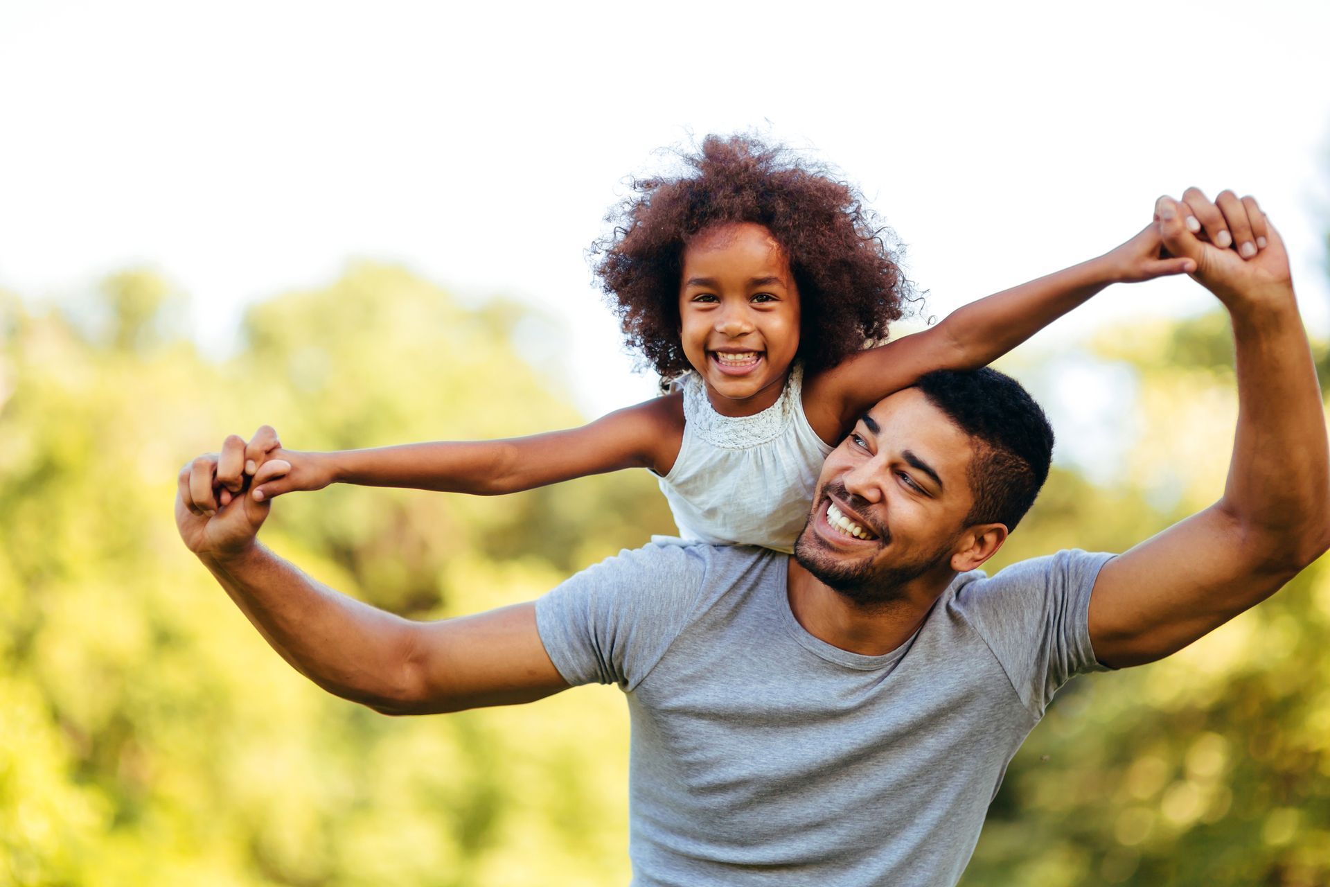 A man is carrying a little girl on his shoulders.