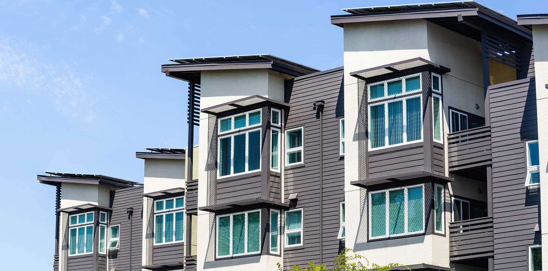A row of apartment buildings with lots of windows against a blue sky.