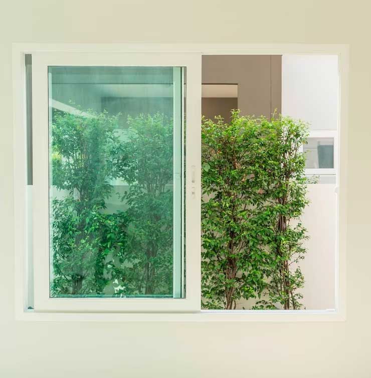 A white window with a green hedge behind it.