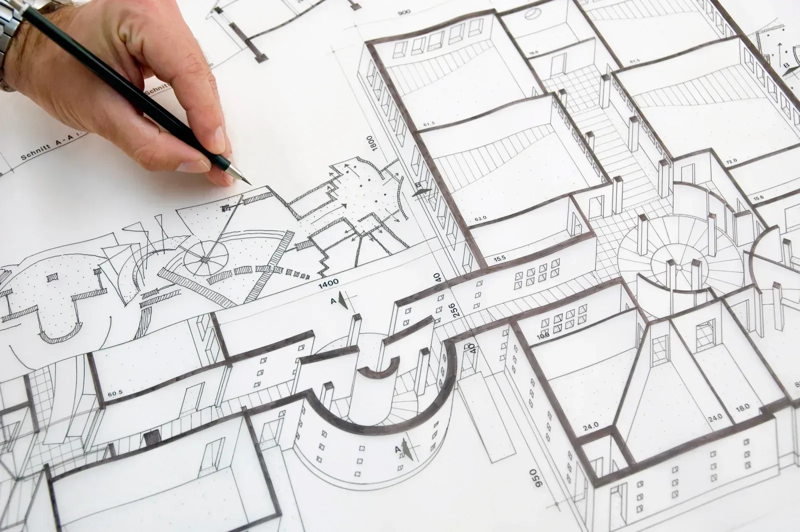 A person is drawing a floor plan of a building with a pencil