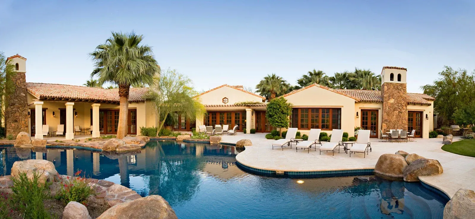 A porch with a table and chairs and a ceiling fan.