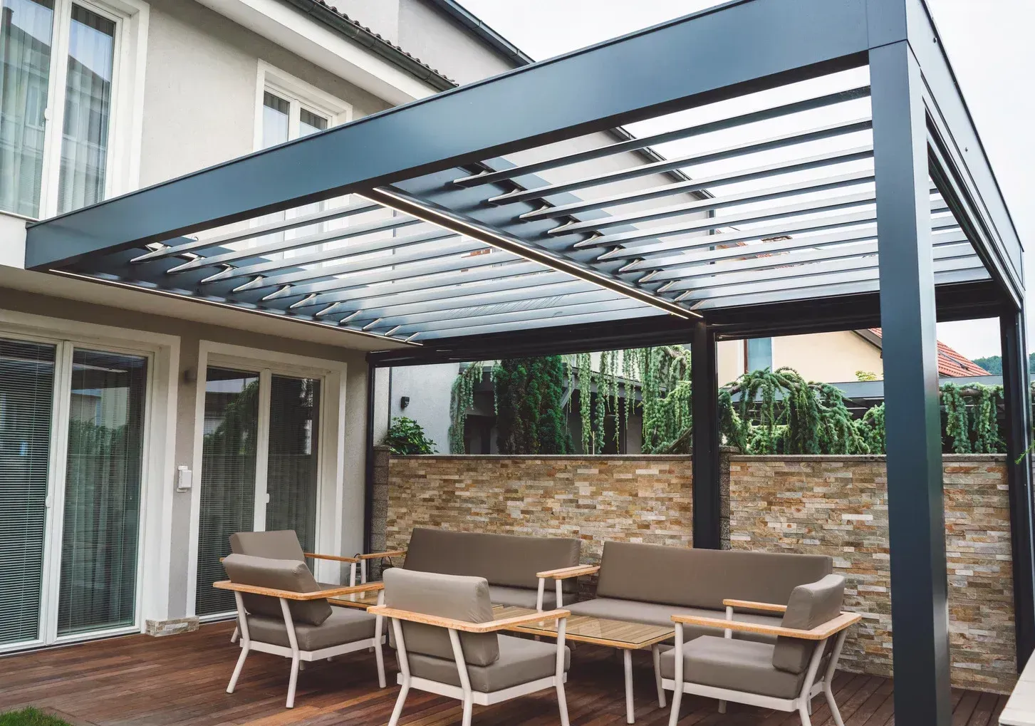 There is a pergola with a couch and chairs underneath it.
