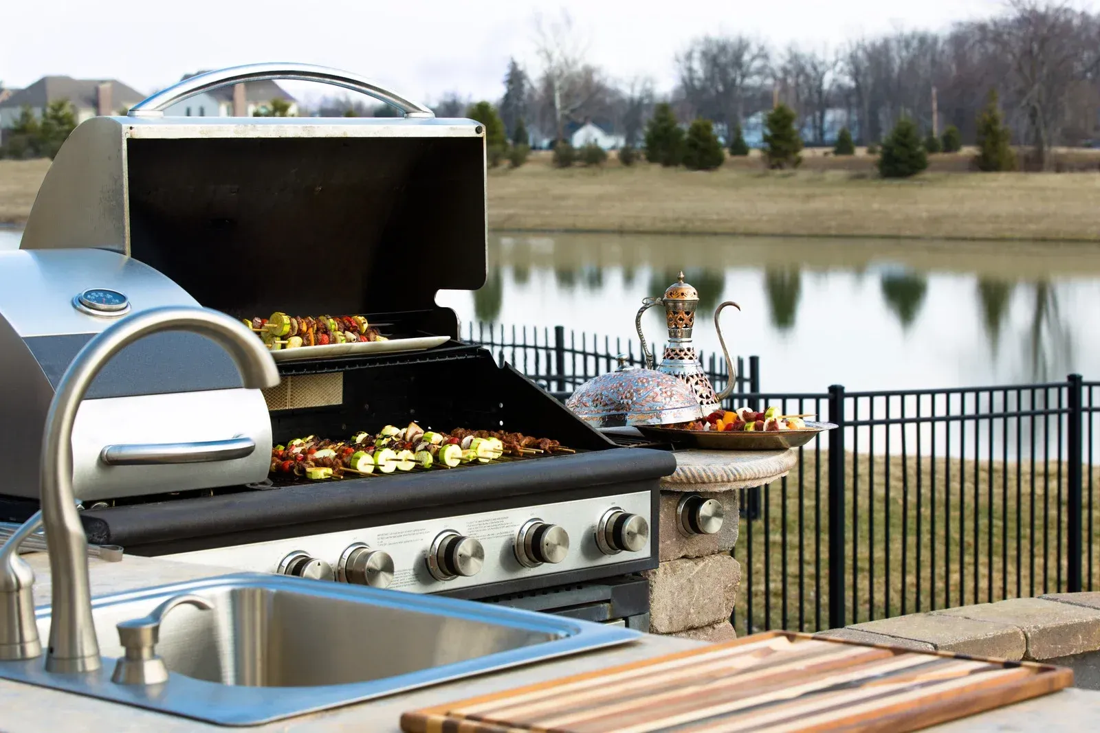 A grill with a sink and a fence in the background