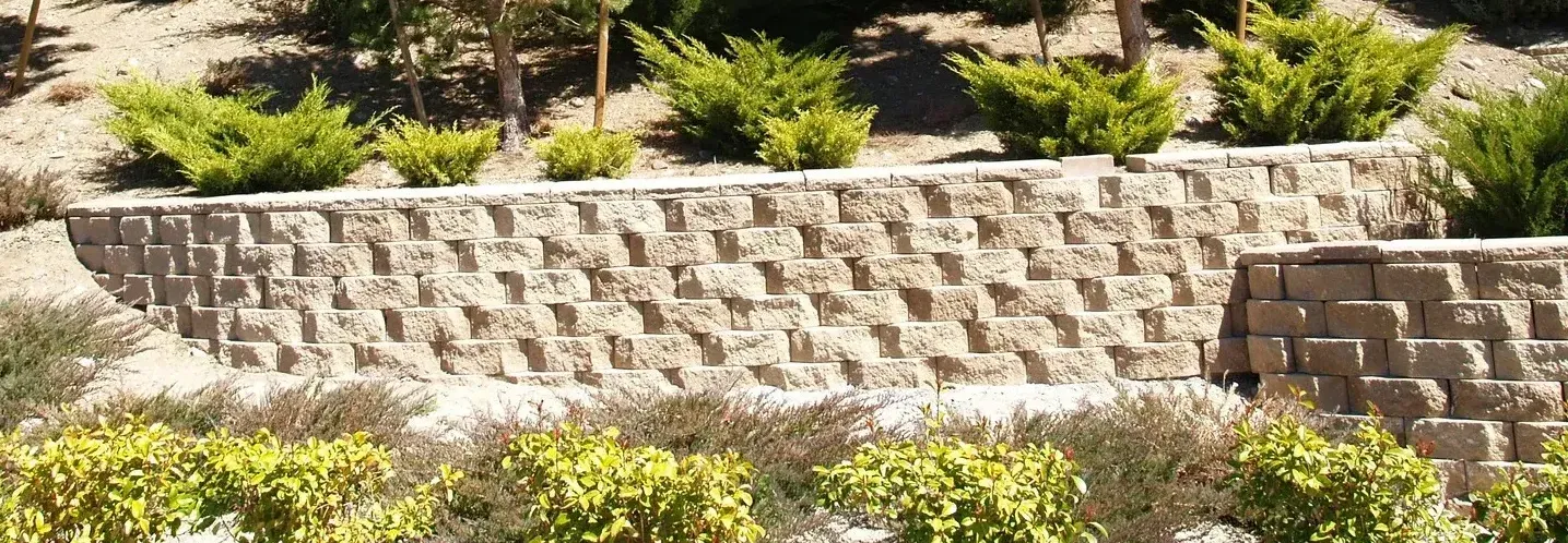 A stone wall surrounded by trees and bushes on a hillside.