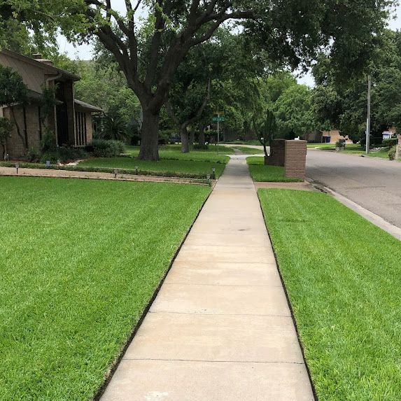 A sidewalk leading to a house with a lush green lawn.