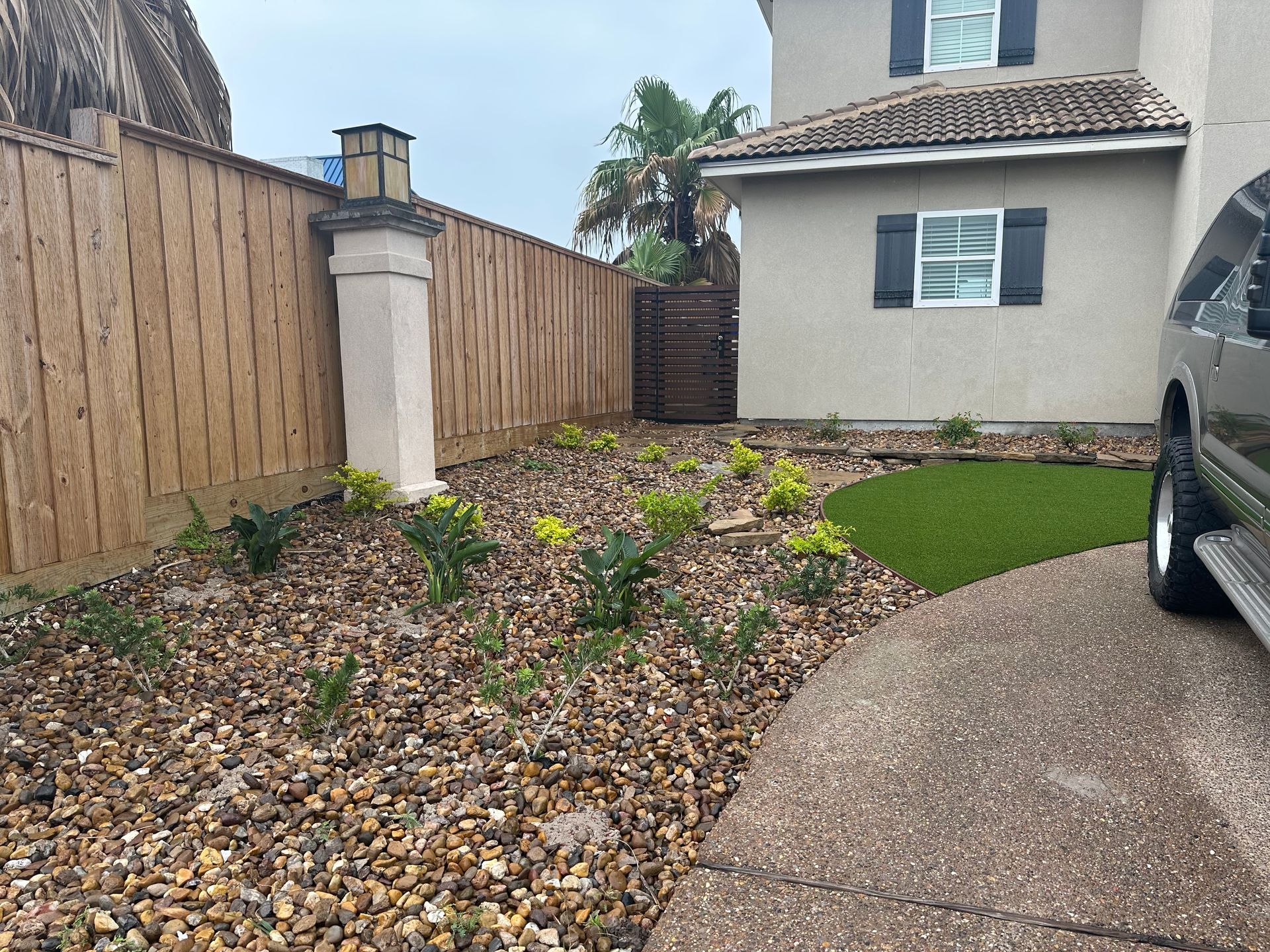 A car is parked in front of a house with a wooden fence.