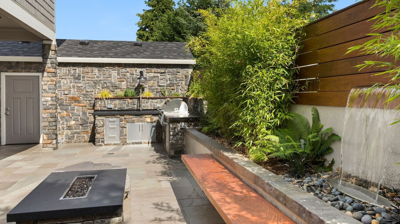 An outdoor kitchen with a fire pit and a wooden bench.