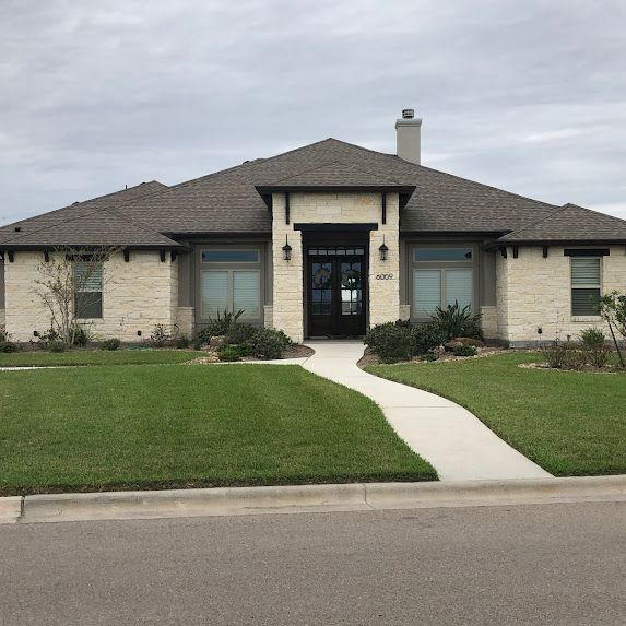 A large brick house with a gray roof and a walkway leading to it.