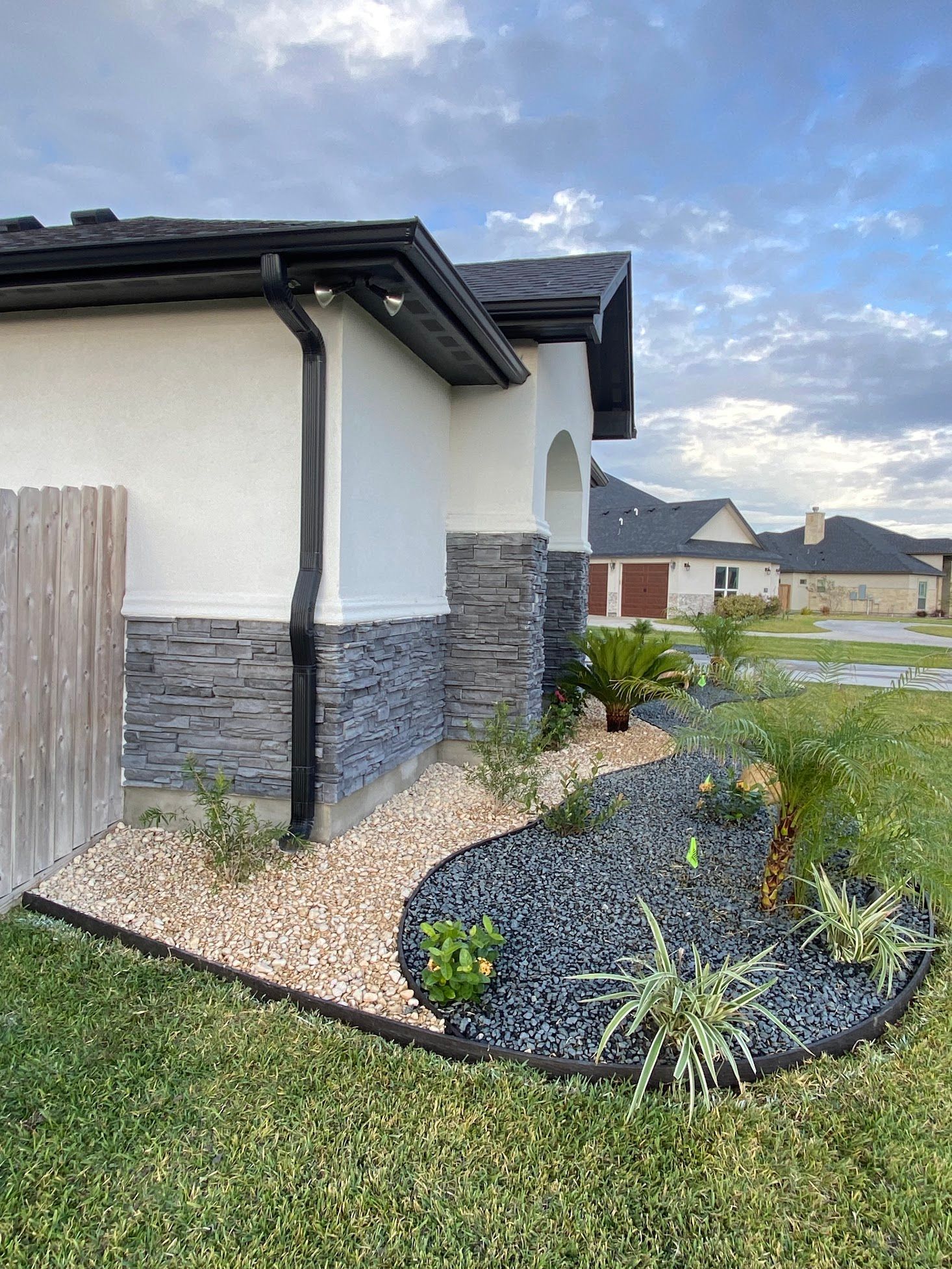 A house with a fence and a garden in front of it.