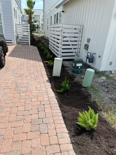A brick walkway leading to a house with a motorcycle parked on the side of it.