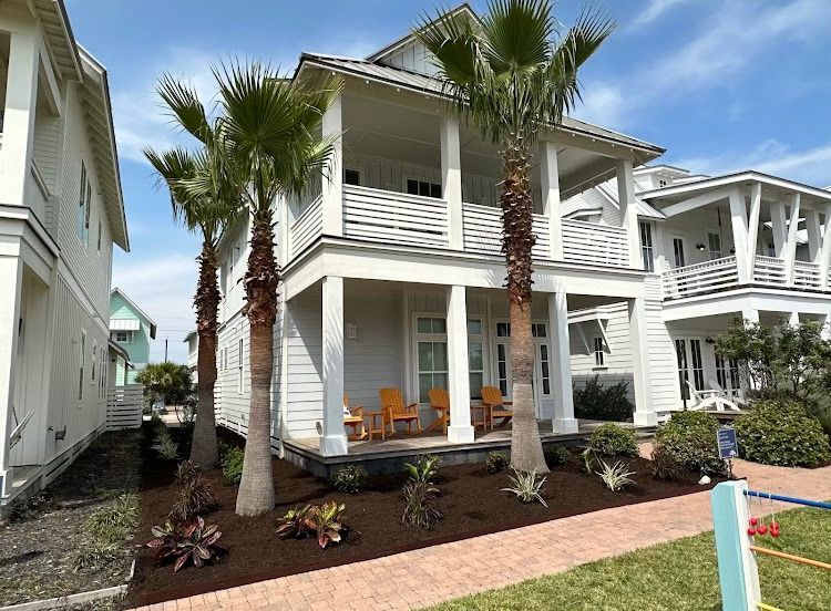 A white house with palm trees in front of it is for sale.