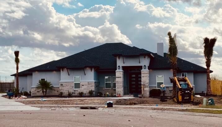 A house with a black roof is being built in a residential area.