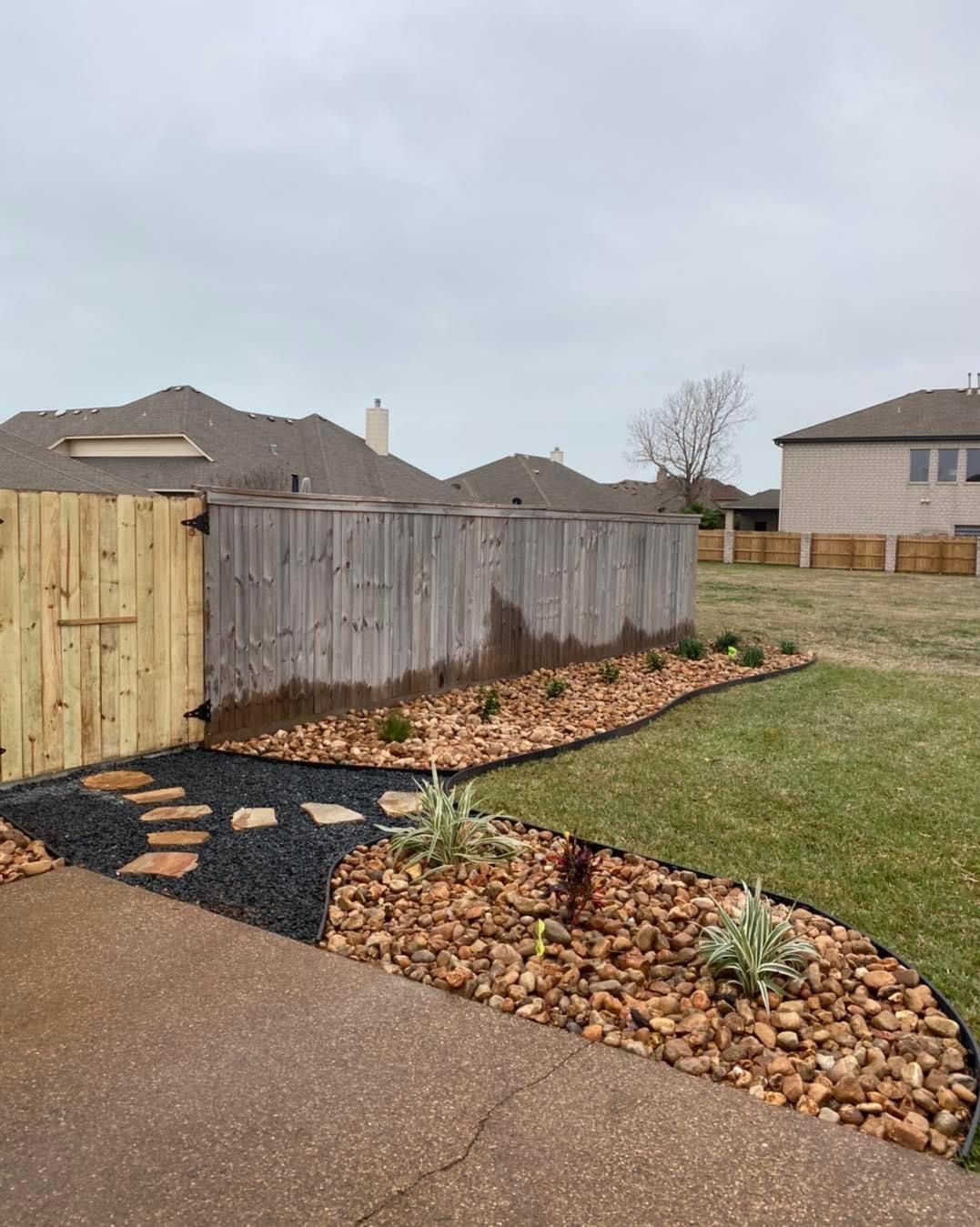 A wooden fence surrounds a lush green yard.