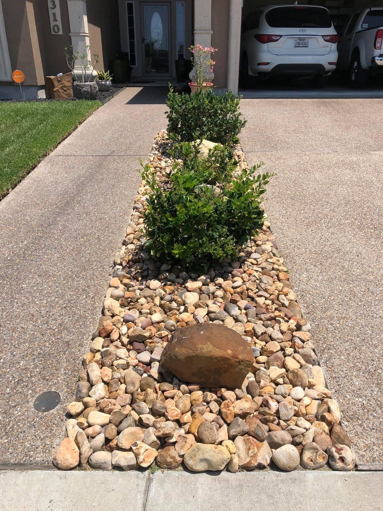 A driveway with rocks and plants in front of a house.