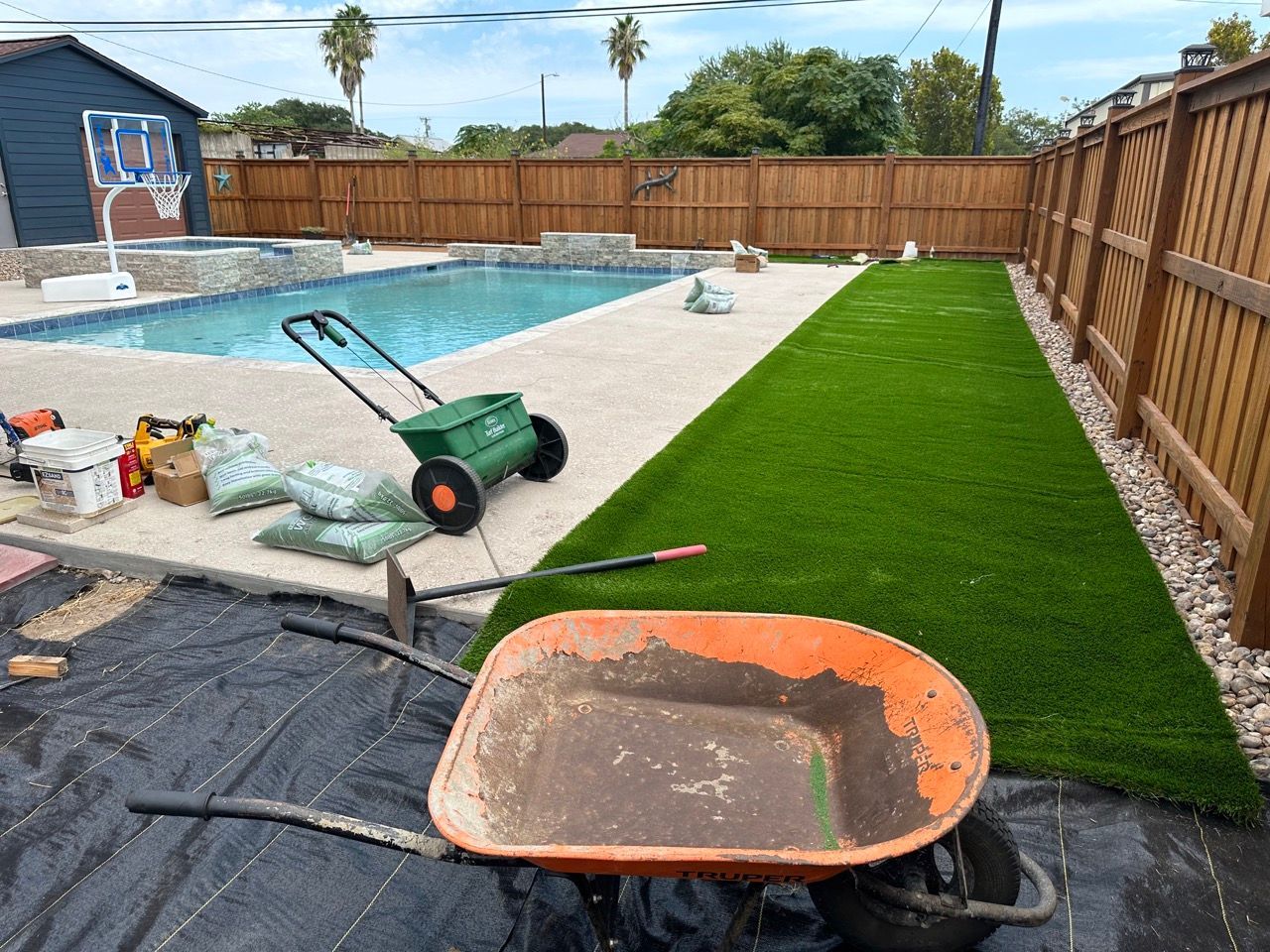 A wheelbarrow is sitting in the middle of a backyard next to a pool.