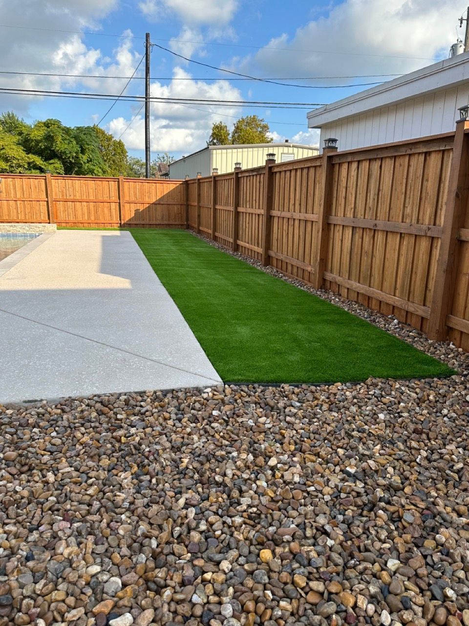 A backyard with a wooden fence and a lawn
