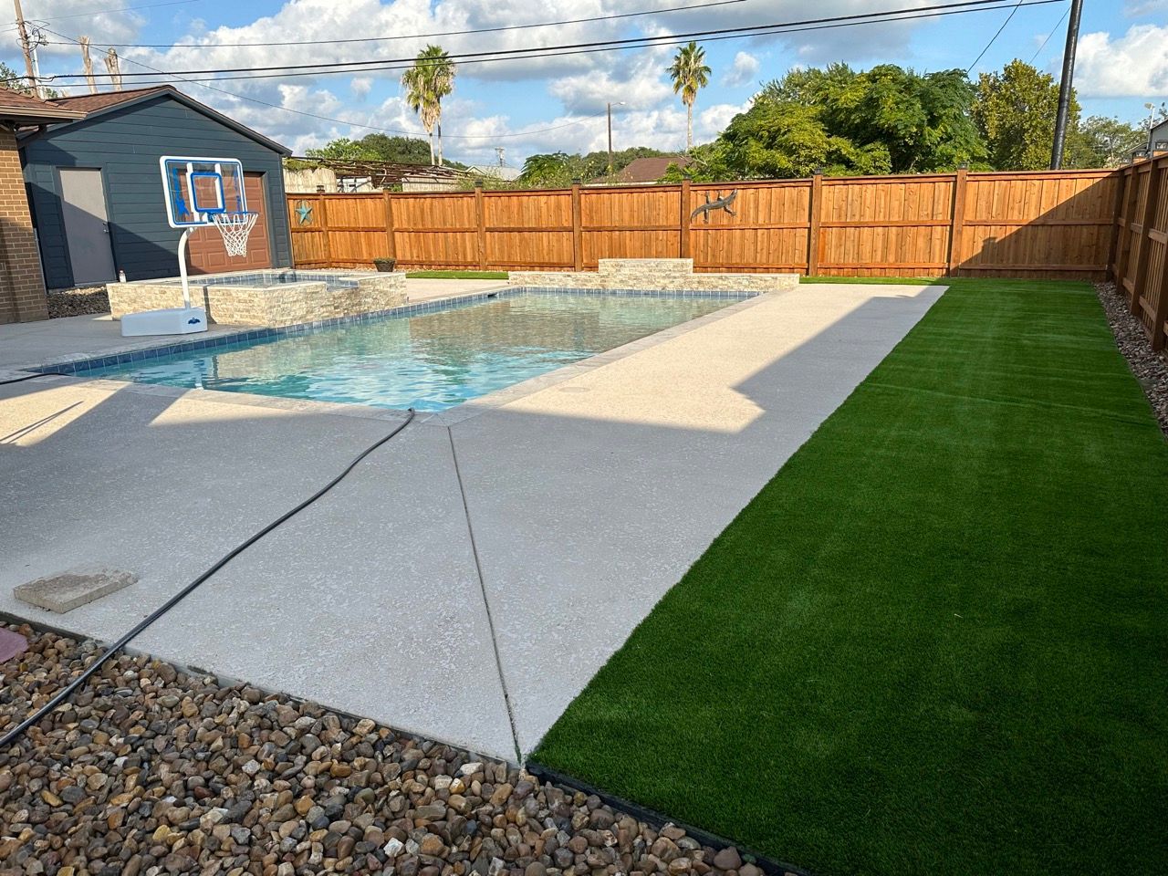 A backyard with a swimming pool and a basketball hoop.