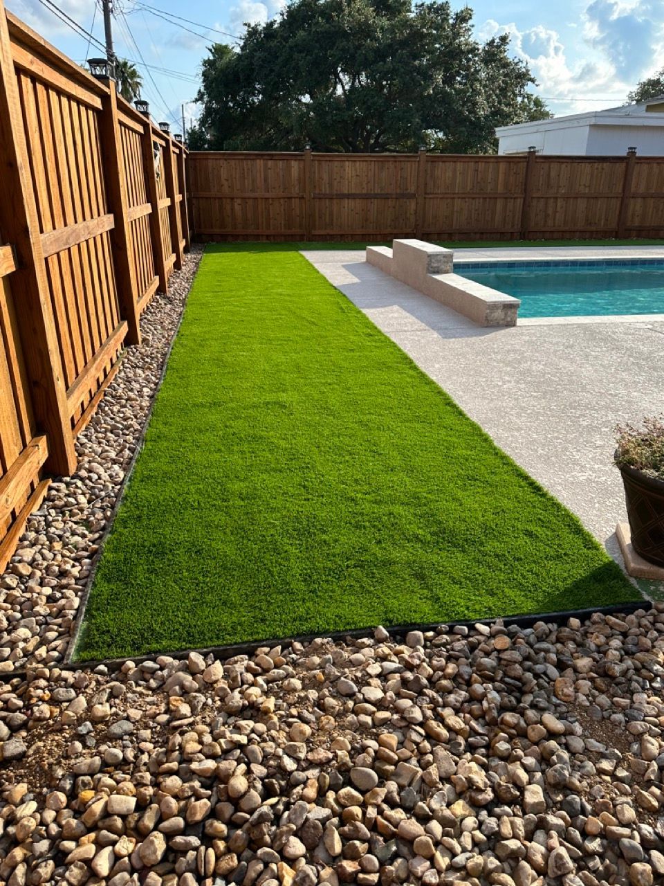 A lawn with a fence and a view of a body of water.