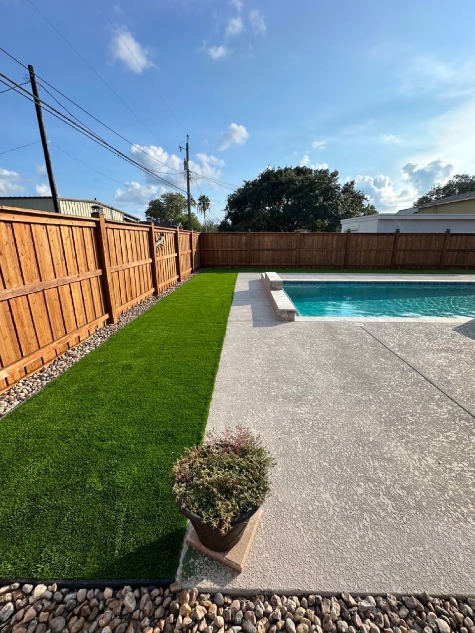 A backyard with a swimming pool and a wooden fence.