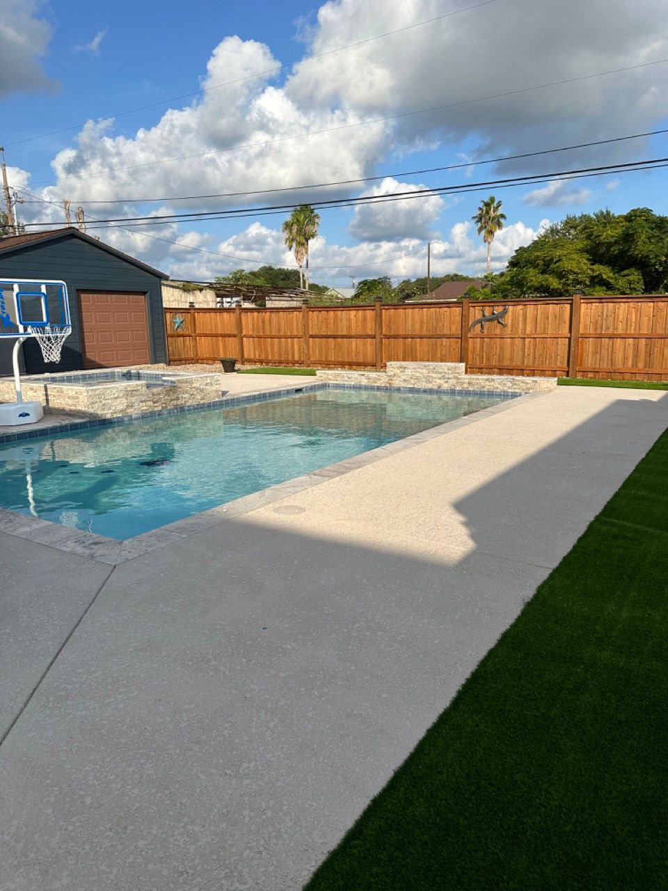 A backyard with a swimming pool and a basketball hoop