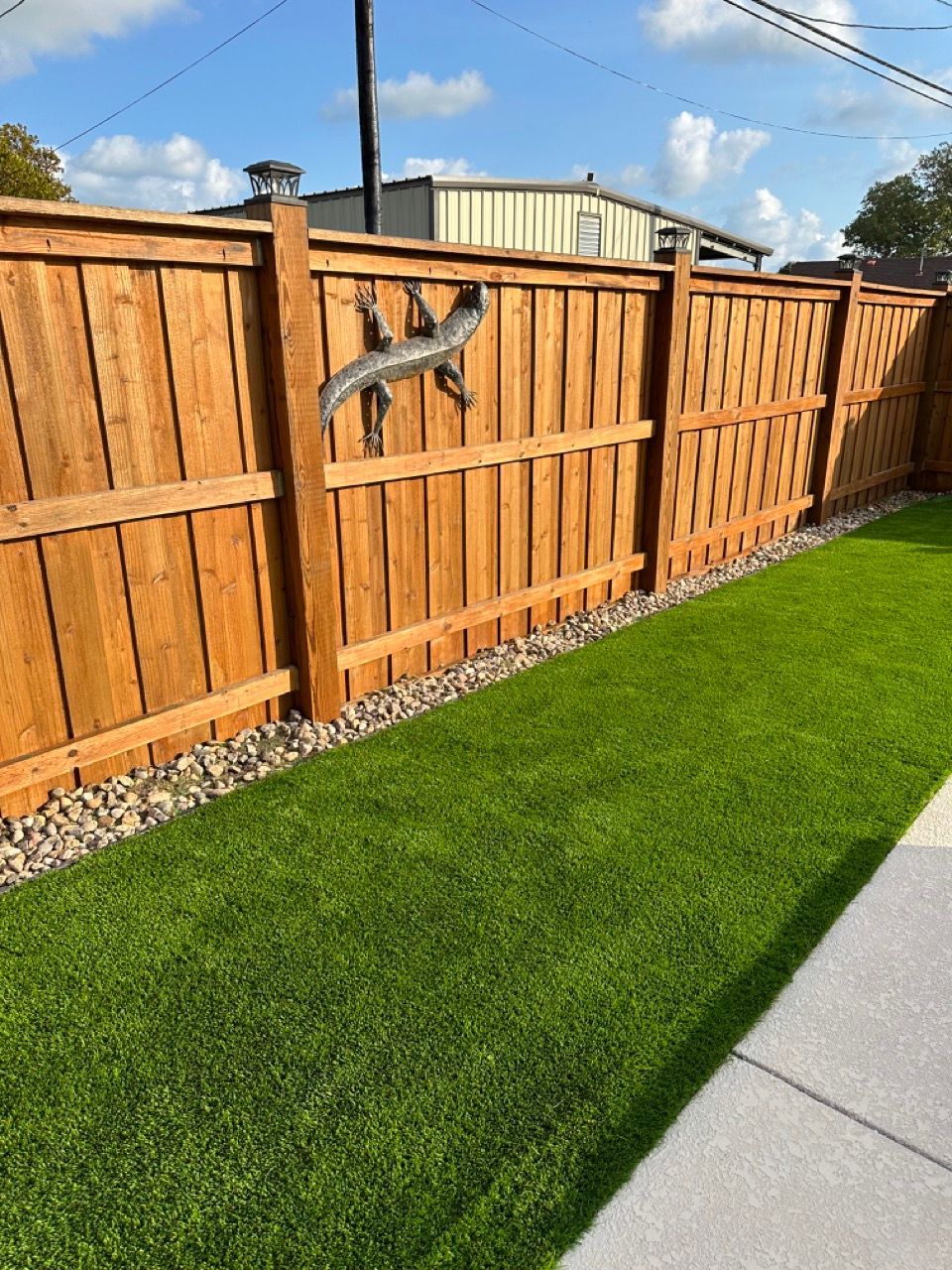 A wooden fence surrounds a lush green lawn.