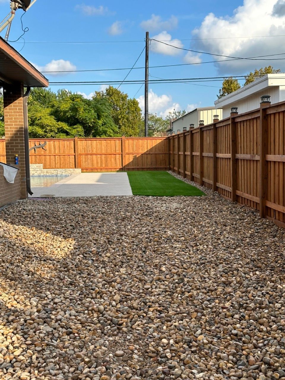 A backyard with a wooden fence and gravel.
