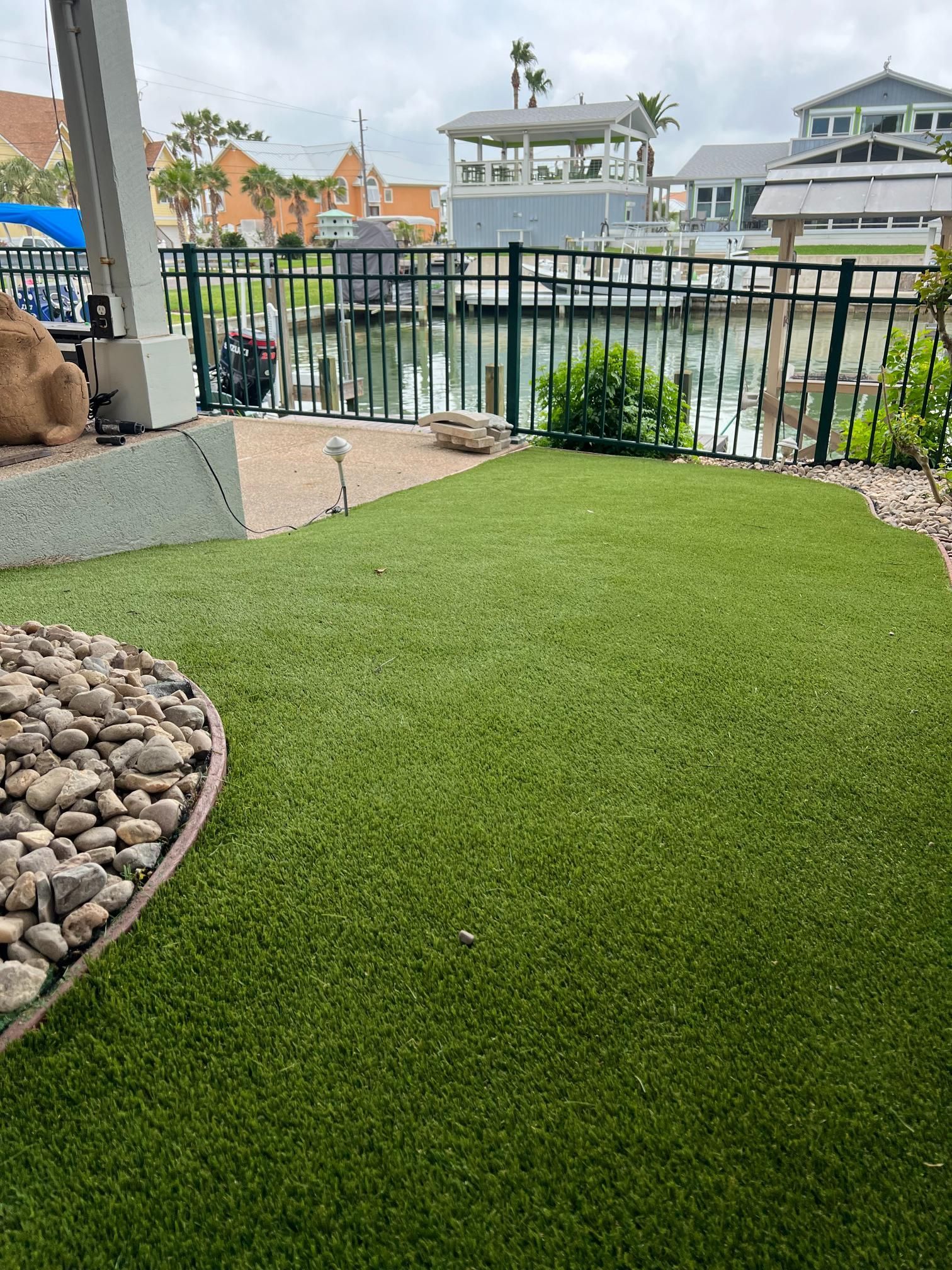 A lawn with a fence and a view of a body of water.