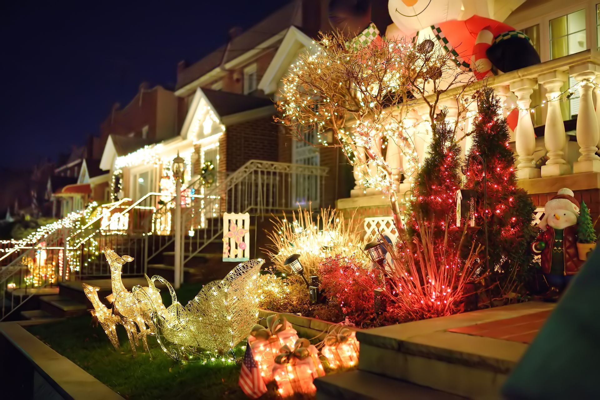 Houses decorated with bright Christmas lights at night.