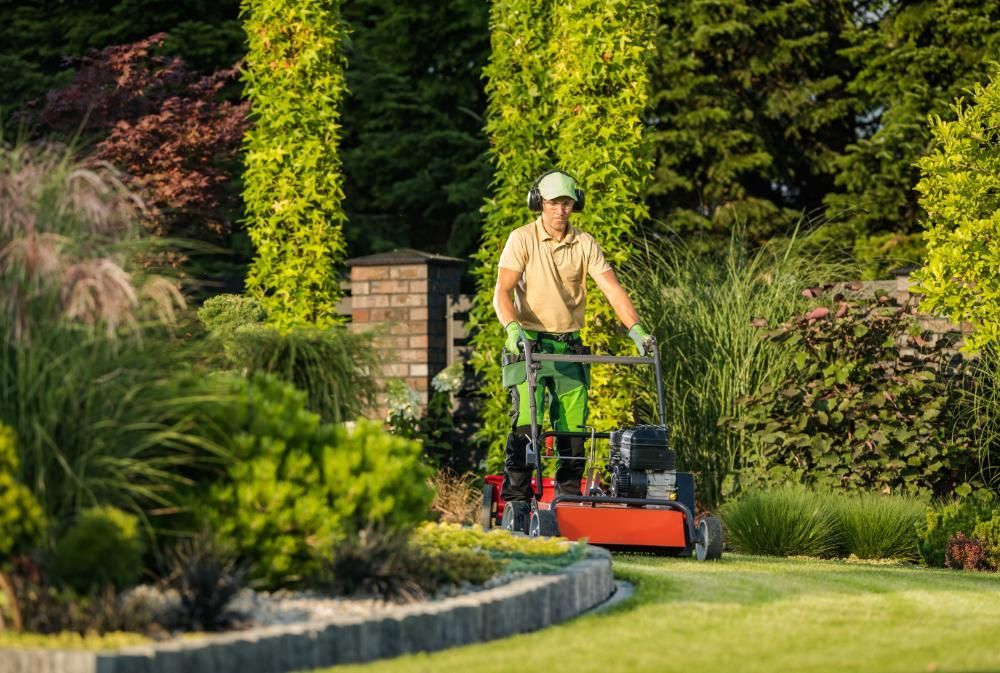 A man is mowing a lush green lawn with a lawn mower.