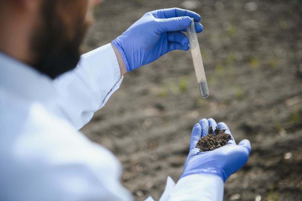 A scientist is holding a test tube and a sample of soil.