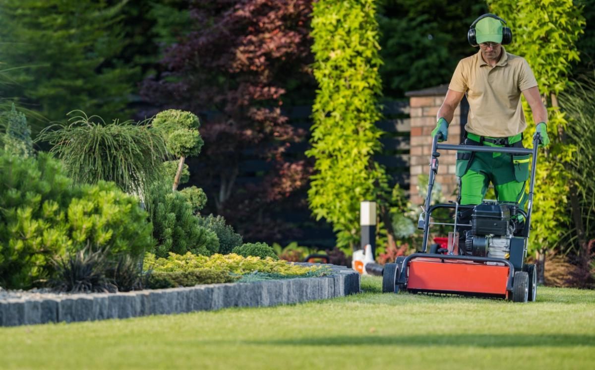 A man is mowing a lush green lawn with a lawn mower.