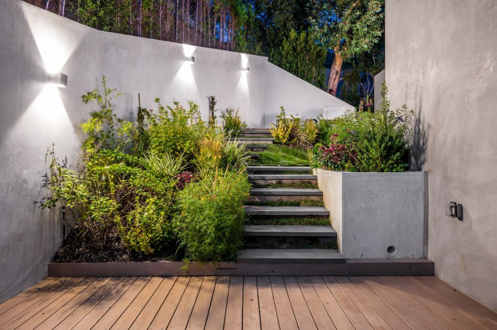 A wooden deck with stairs leading up to a garden.