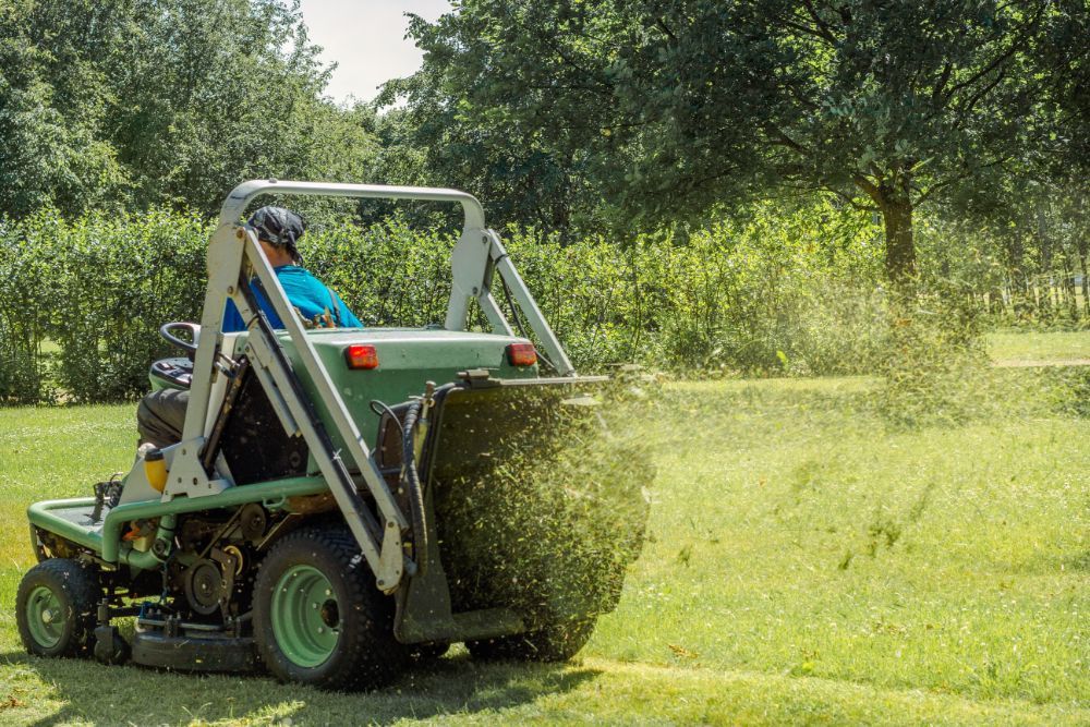 A man is riding a lawn mower through a grassy field.