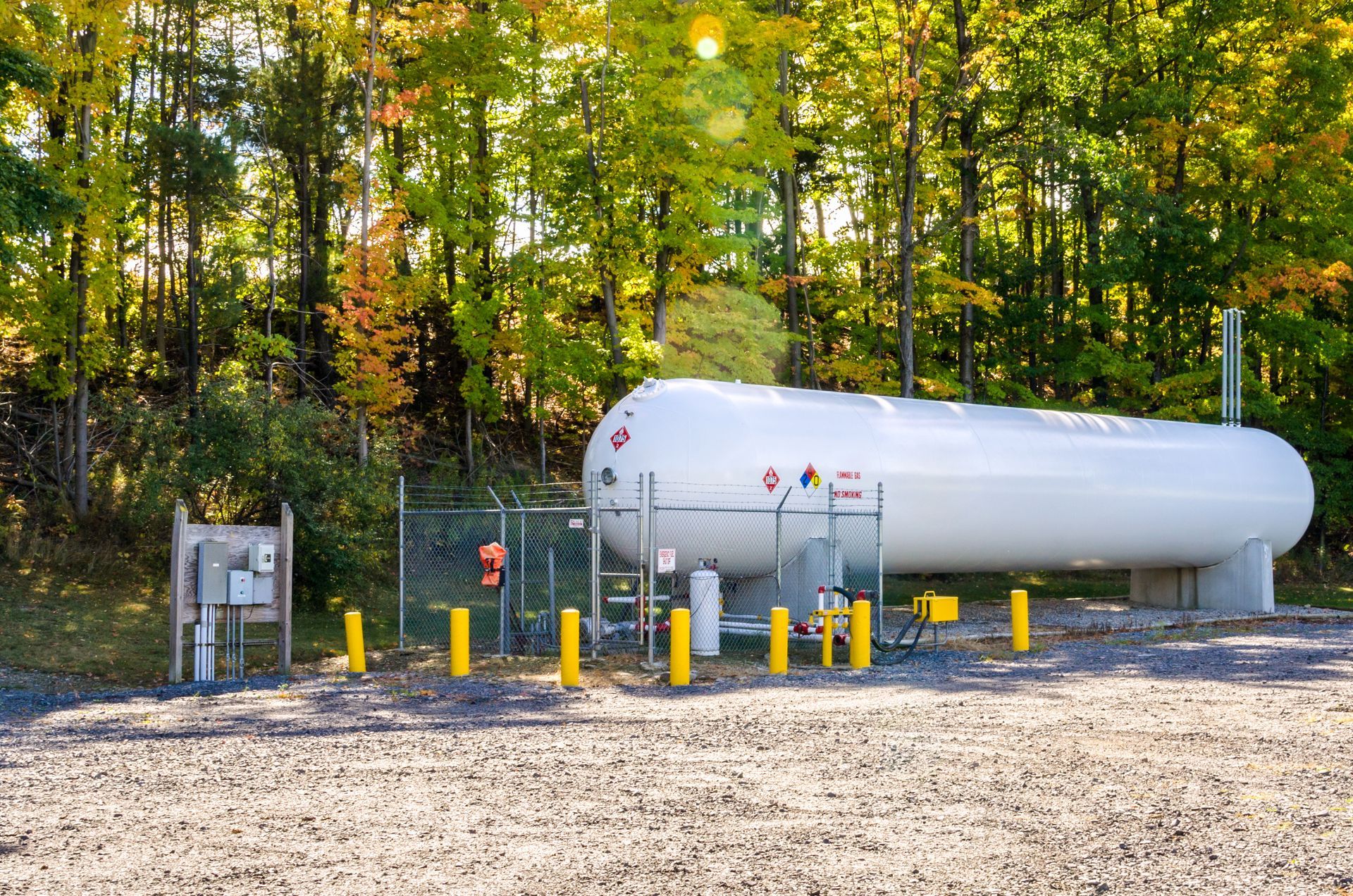 View of a white bulk propane tank on a sunny autumn day