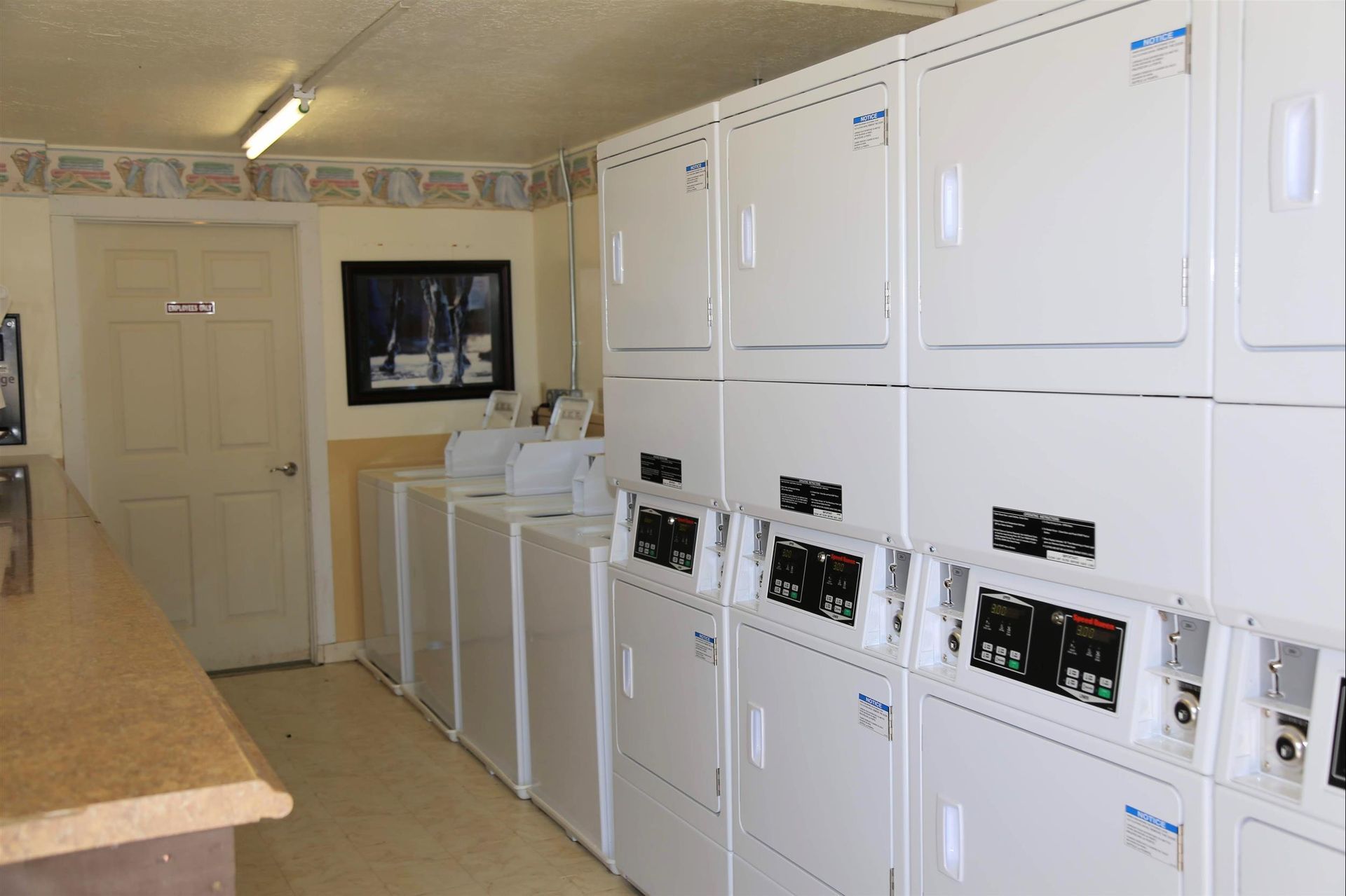 A laundromat with a lot of white washers and dryers