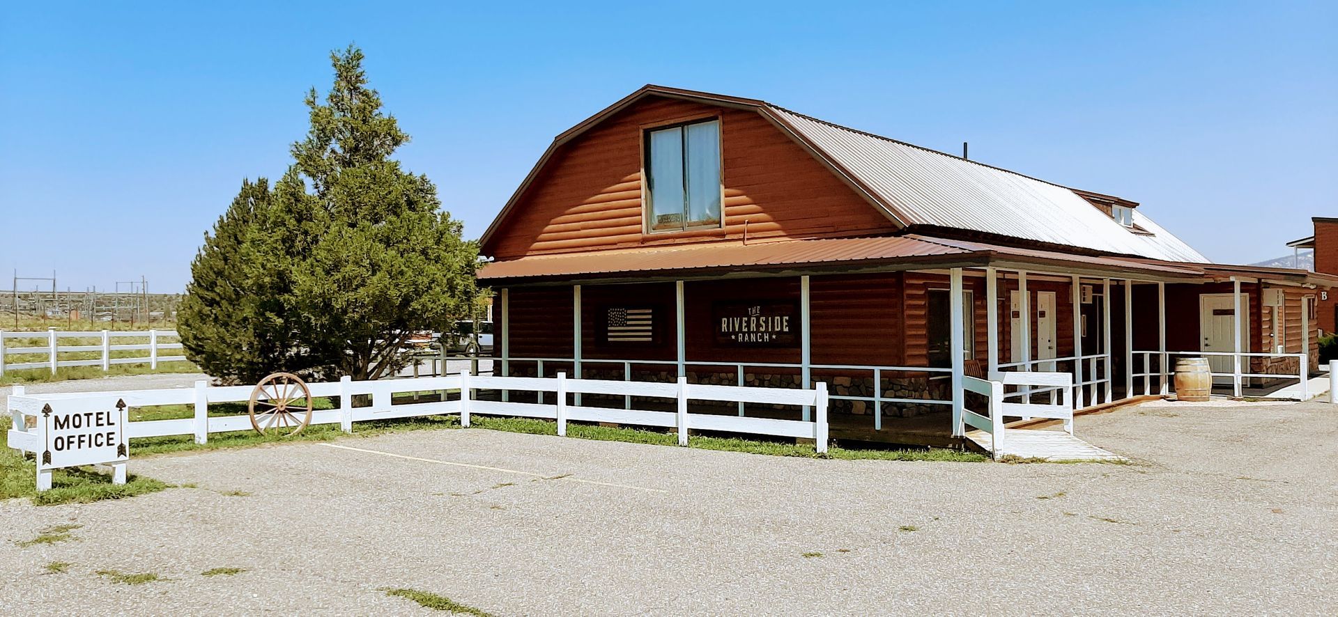 A large barn with a white fence around it