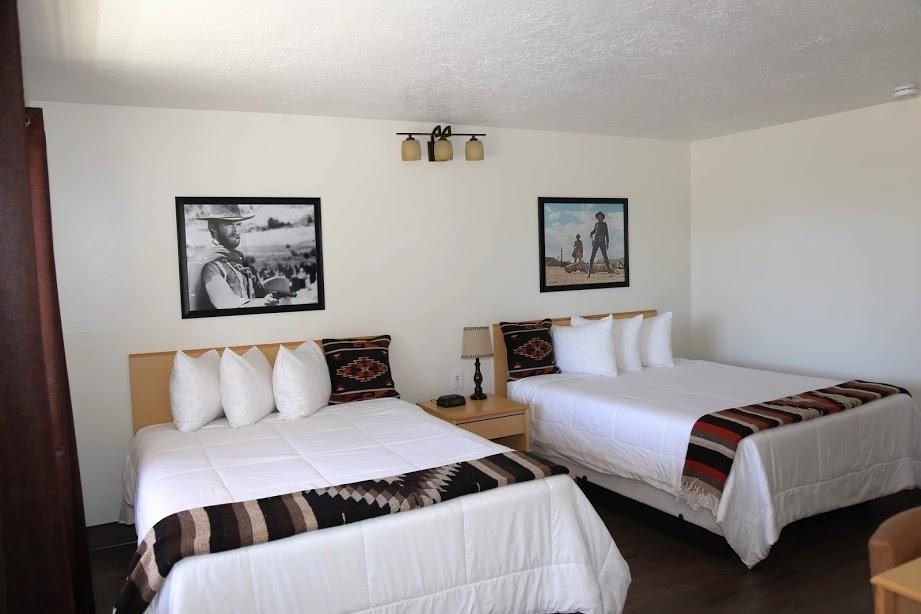 A hotel room with two beds and two pictures on the wall.