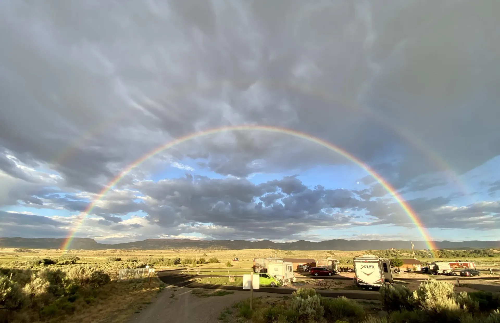 There is a double rainbow in the sky over a campground.