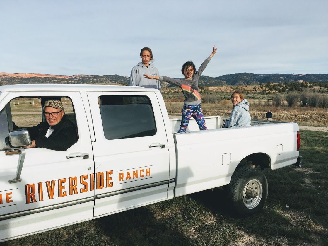 A group of people are standing in the back of a white truck.