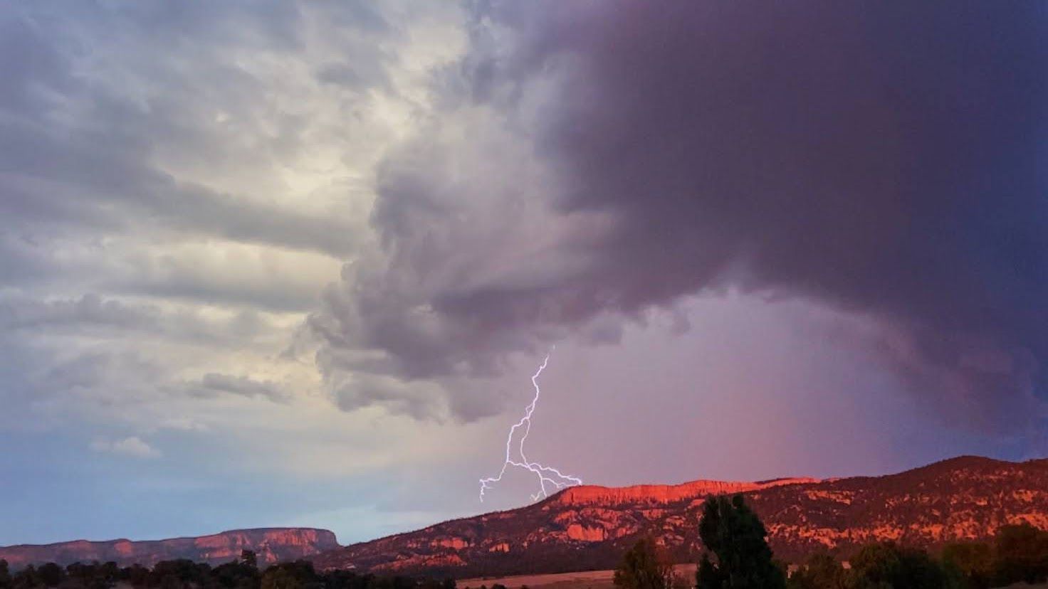 There is a lightning bolt in the sky over a mountain.