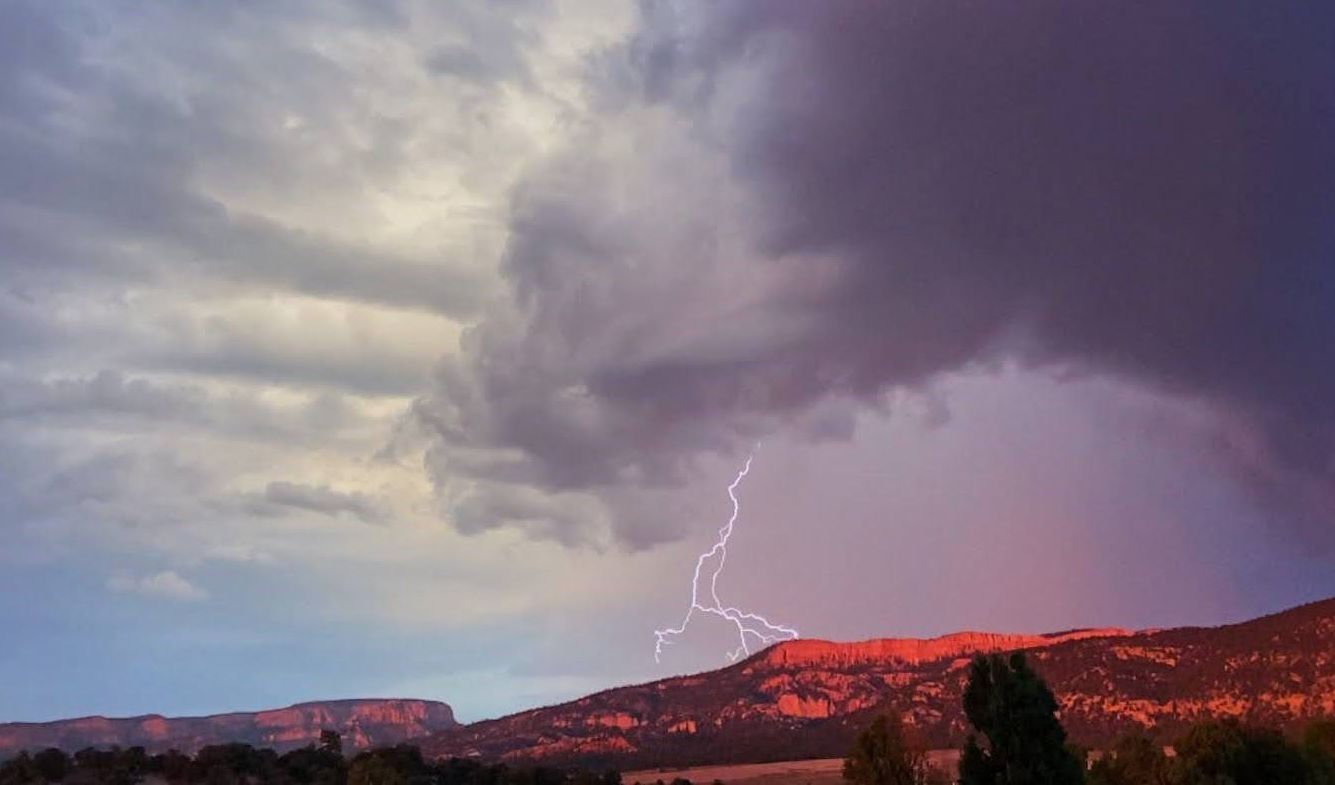 There is a lightning bolt in the sky over a mountain.