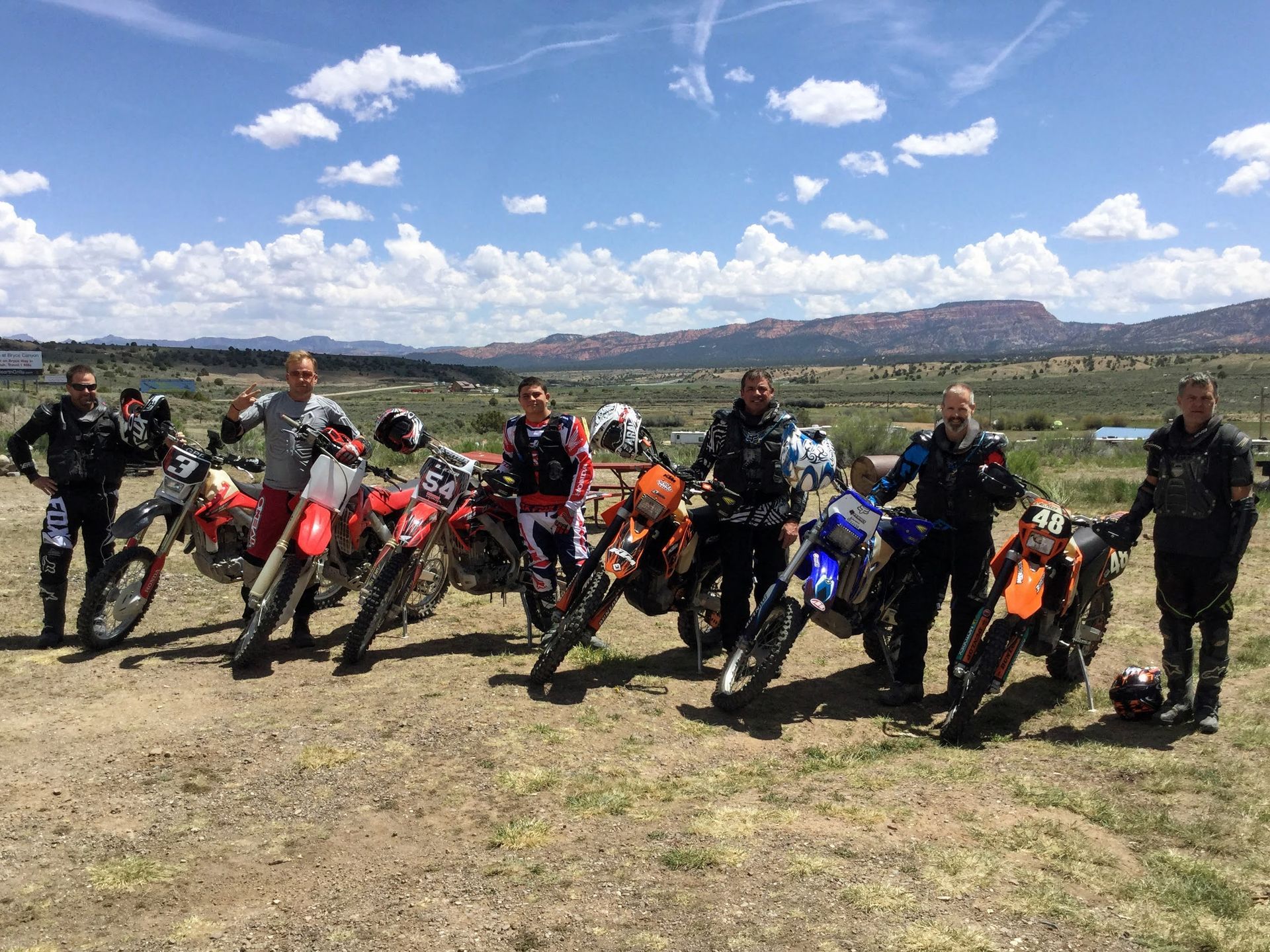 A group of people standing next to motorcycles in a field.