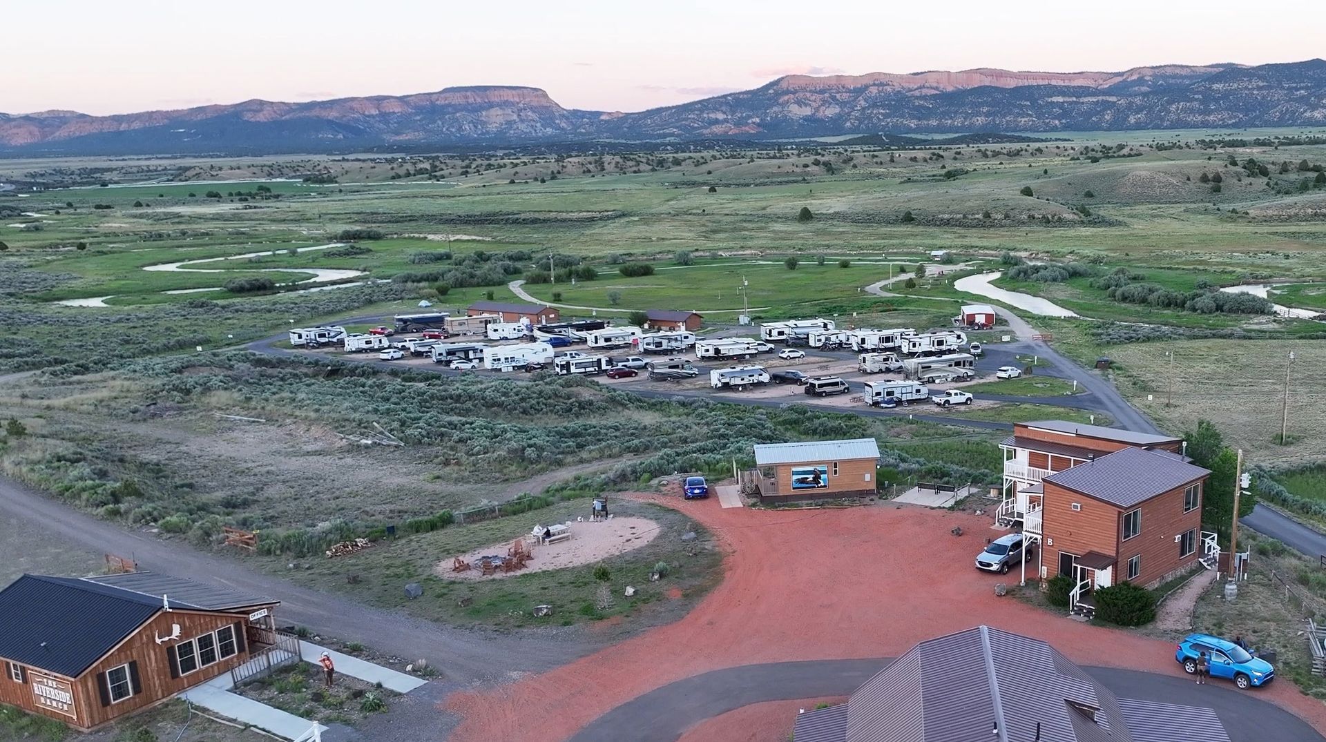 An aerial view of a small town in the middle of a field with mountains in the background.