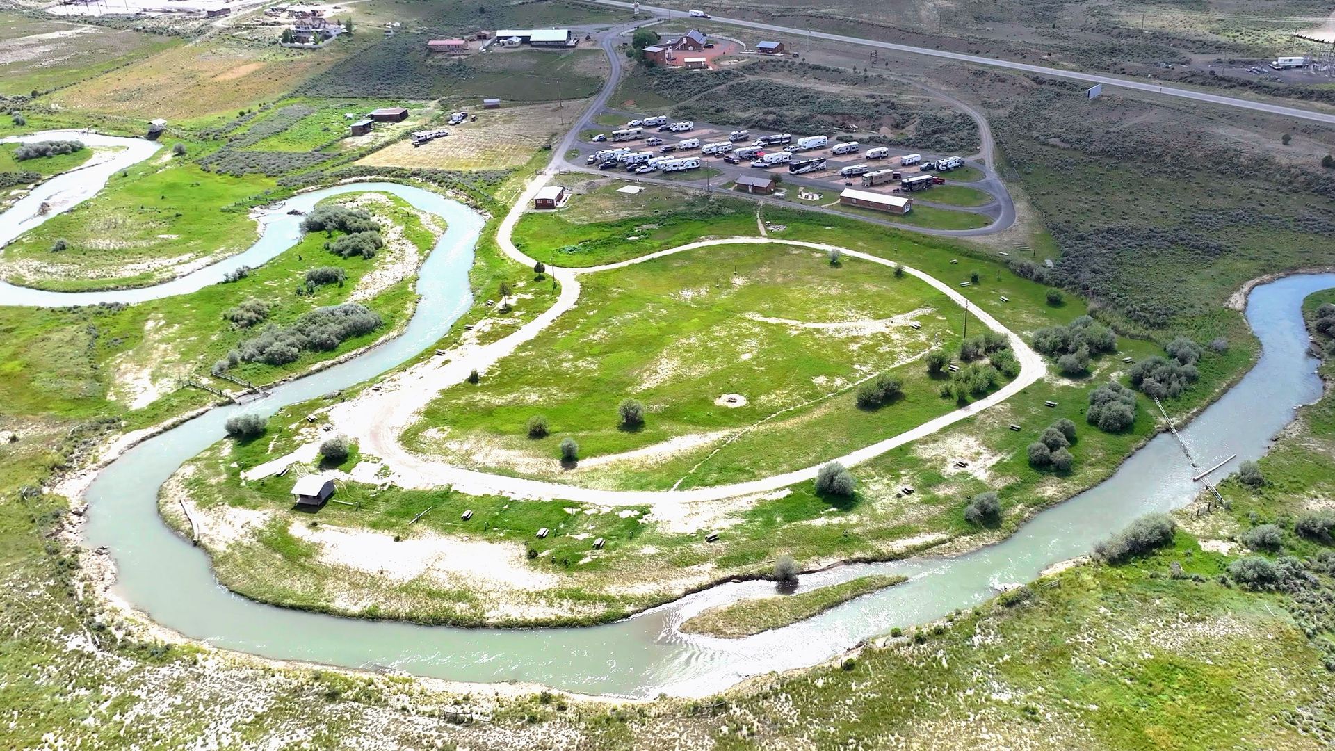 An aerial view of a river surrounded by grass and trees