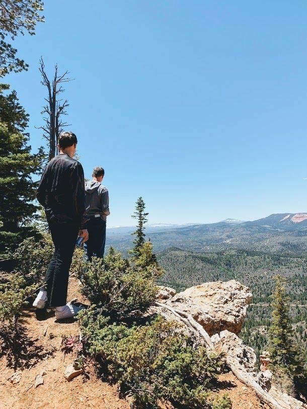Two people are standing on top of a mountain looking at the view.