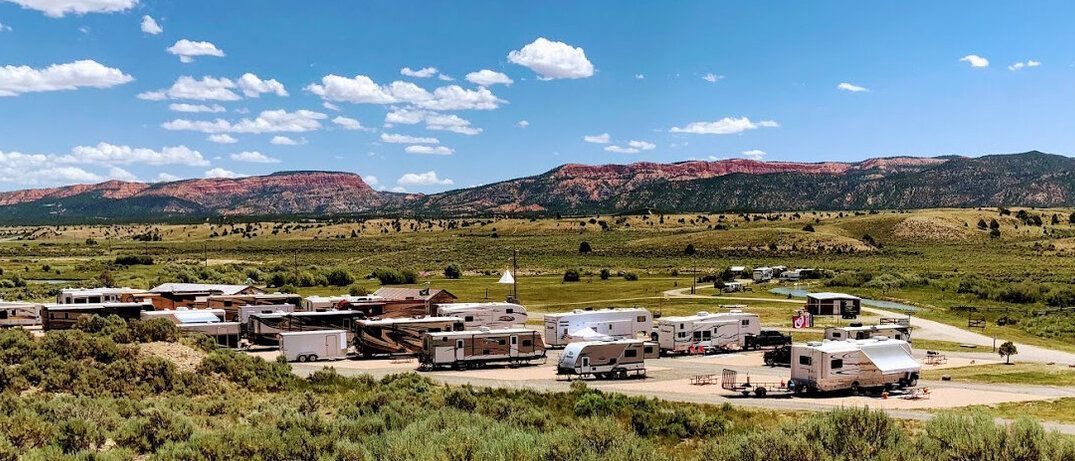 A group of rvs are parked in a field with mountains in the background.